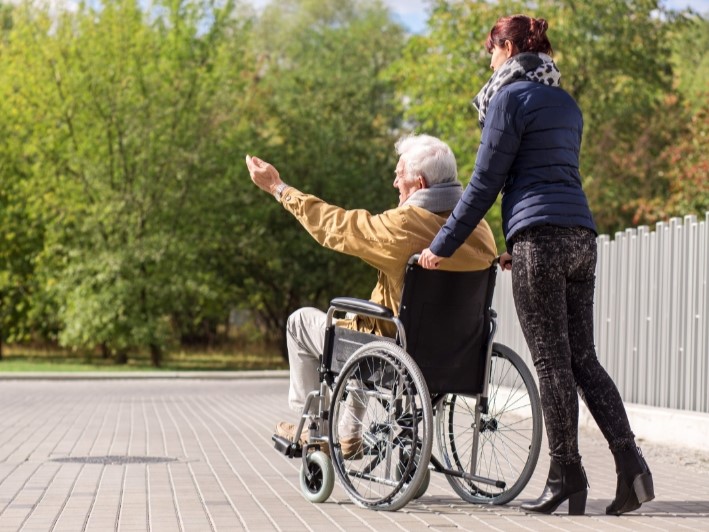 Osoba poruszająca się na wózku inwalidzkim wraz z opiekunem.