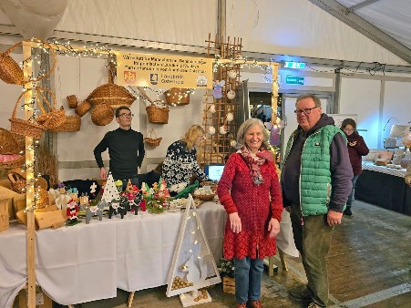 Uczestnicy WTZ prowadzący swoje stoisko na Jarmarku Bożonarodzeniowym w Osterholz-Scharbeck, oraz osoby zainteresowane wyrobami.