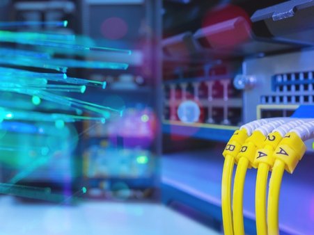 Obraz ilustracyjny przedstawiający światłowód i bliżej nieokreślony fragment sprzętu informatycznego z wtyczkami