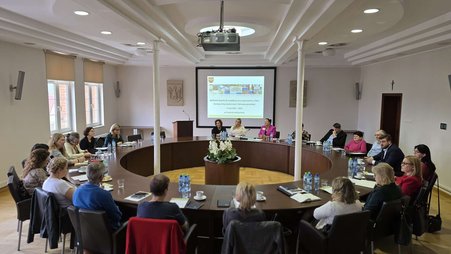 na zdjęciu znajduje się grupa 22 osób siedząca przy okrągłym stole podczas spotkania