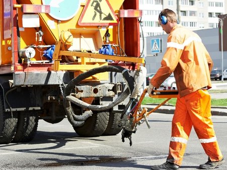 Mężczyzna używa maszyny do naprawy nawierzchni drogi.