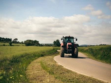 Traktor w trakcie wykaszania pobocza jezdni.