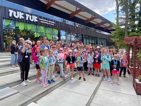 Dzieci z rodzin zastępczych wraz z opiekunami pozują do zdjęcia pamiątkowego przed wejściem do Orientarium ZOO w Łodzi.