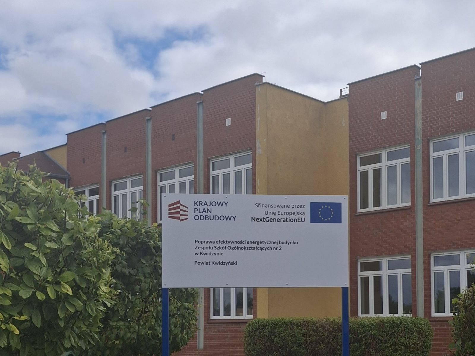 tablica informacyjna o projekcie na tle budynku Zespołu Szkół Ogólnokształcących w Kwidzynie