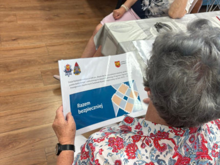 zdjęcie przedstawia starszą osobę trzymającą w ręce plakat projektu. 