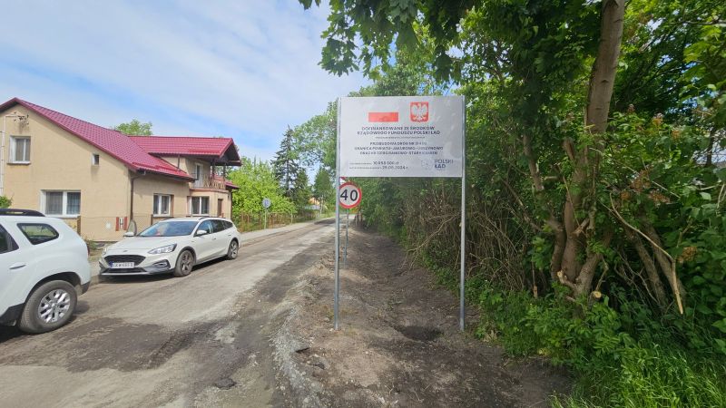 tablica informacyjna na tle remontowanej drogi w miejscowości Obrzynowo