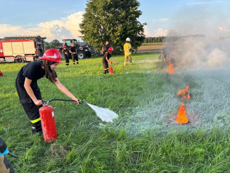 zdjęcie przestawia dzieci gaszące „mały” pożar, podczas ćwiczeń pożarowych