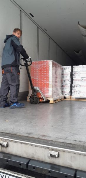 zdjęcie przedstawia stażystę podczas stażu uczniowskiego. Układa on towar na naczepę samochodu dostawczego;